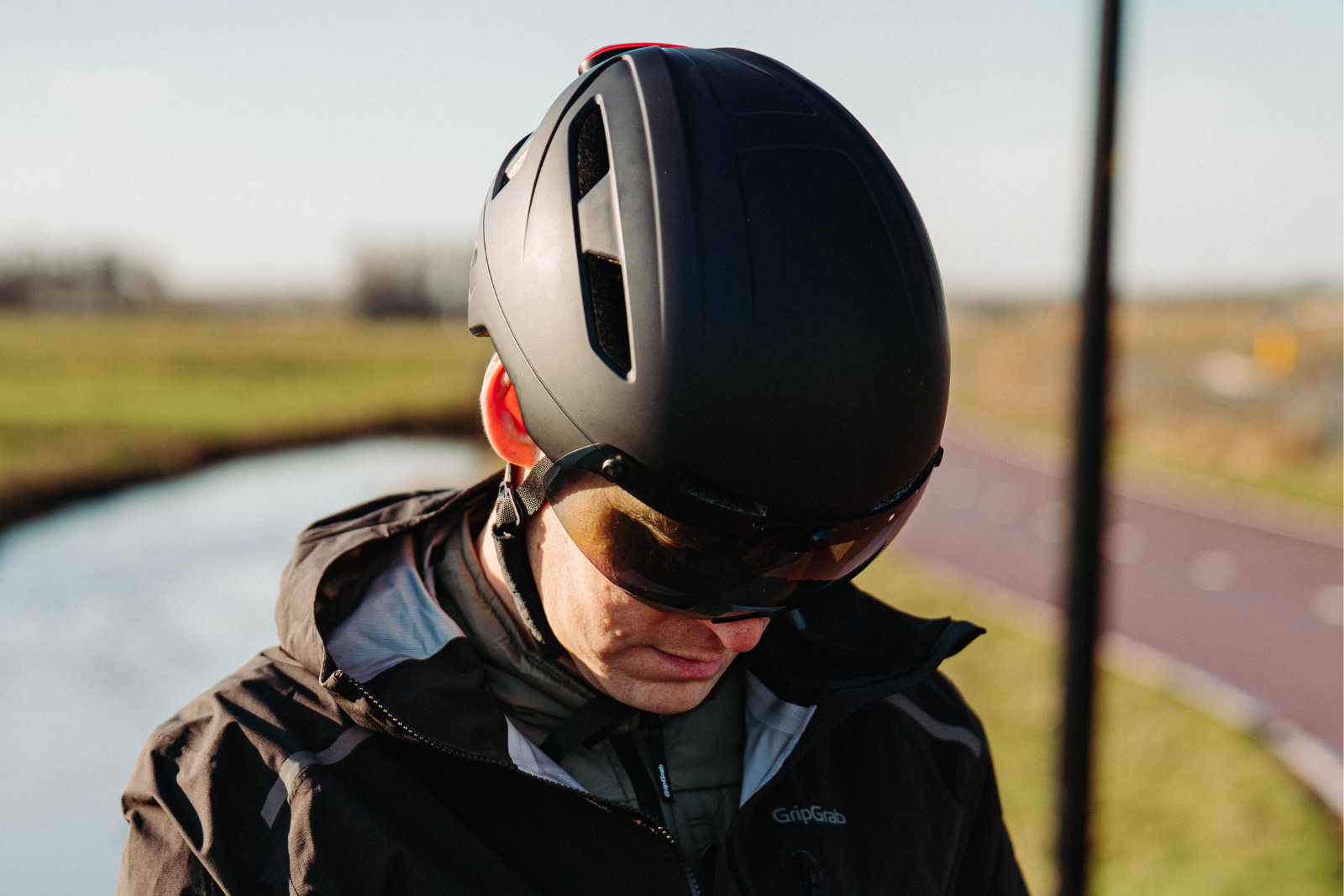 Man draagt een zwarte fietshelm met vizier tijdens een fietstocht.