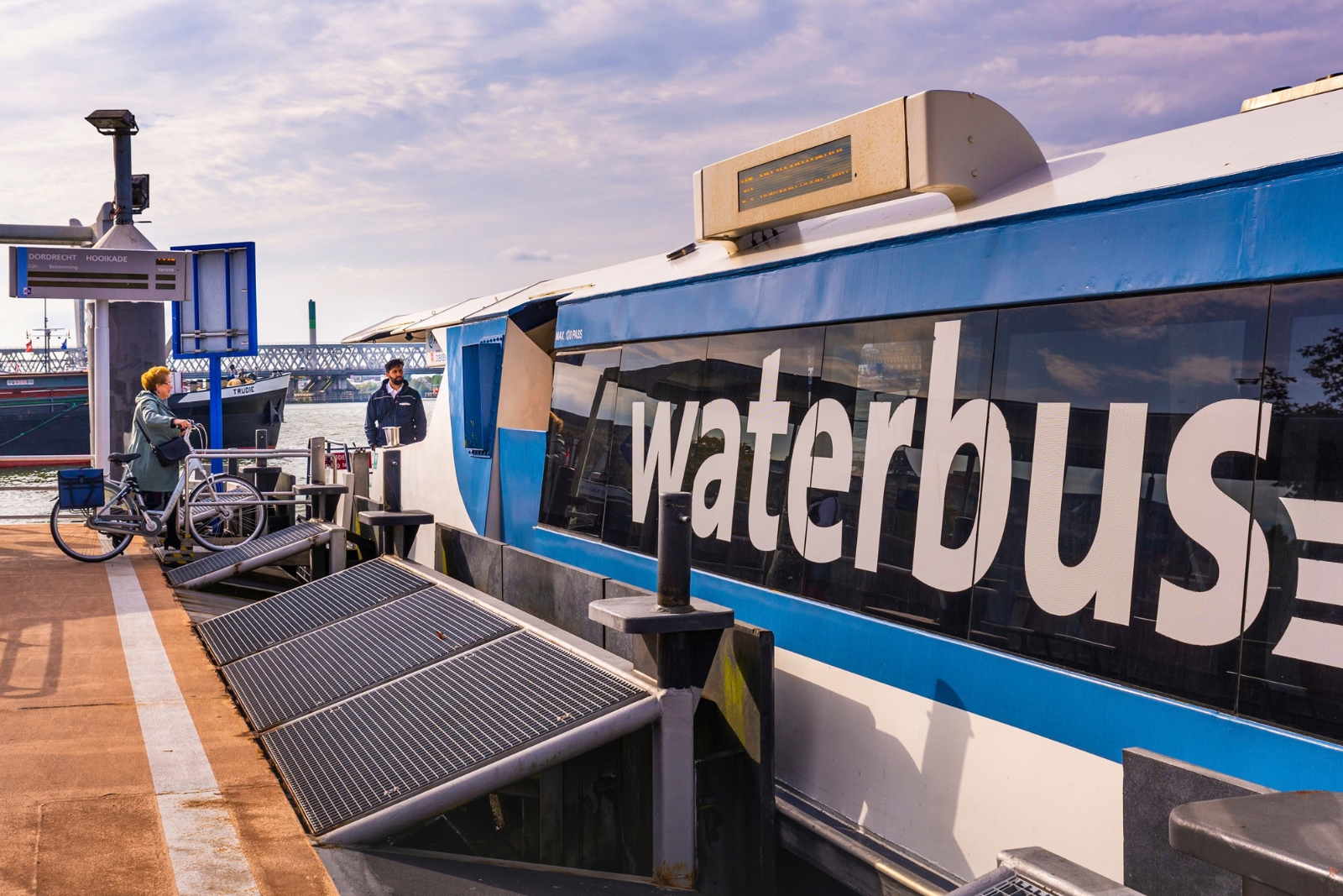 Fietser stapt met de fiets aan boord van de Waterbus bij de Hooikade in Dordrecht.