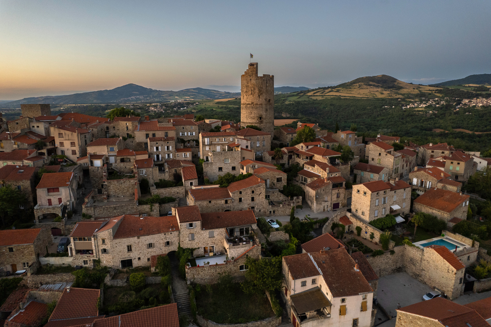 Uitzicht over het historische dorp Montpeyroux in de Auvergne, met stenen huizen, rode daken en de middeleeuwse toren.