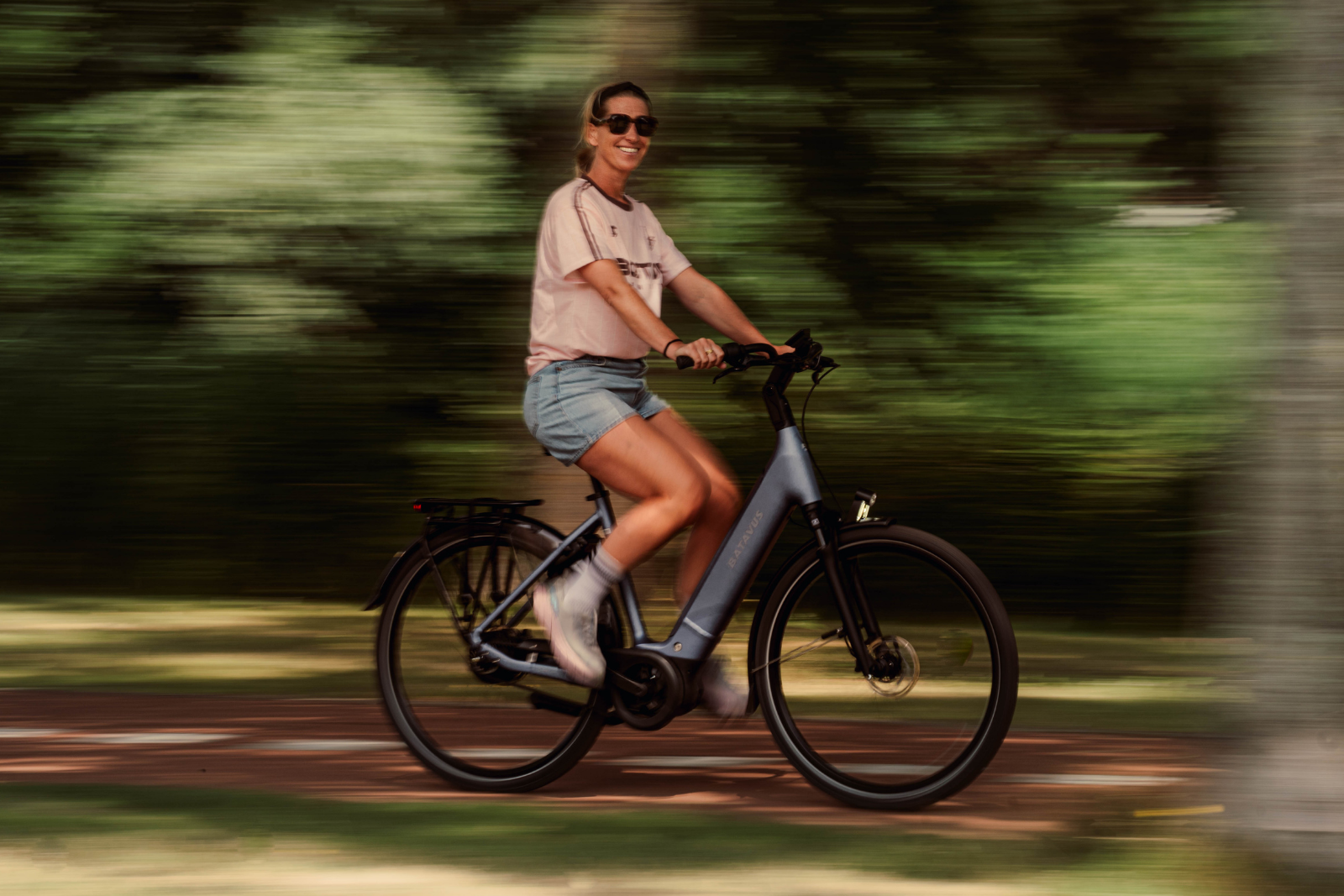 Vrouw fietst op een Batavus Finez PT Exclusive Plus over een fietspad.