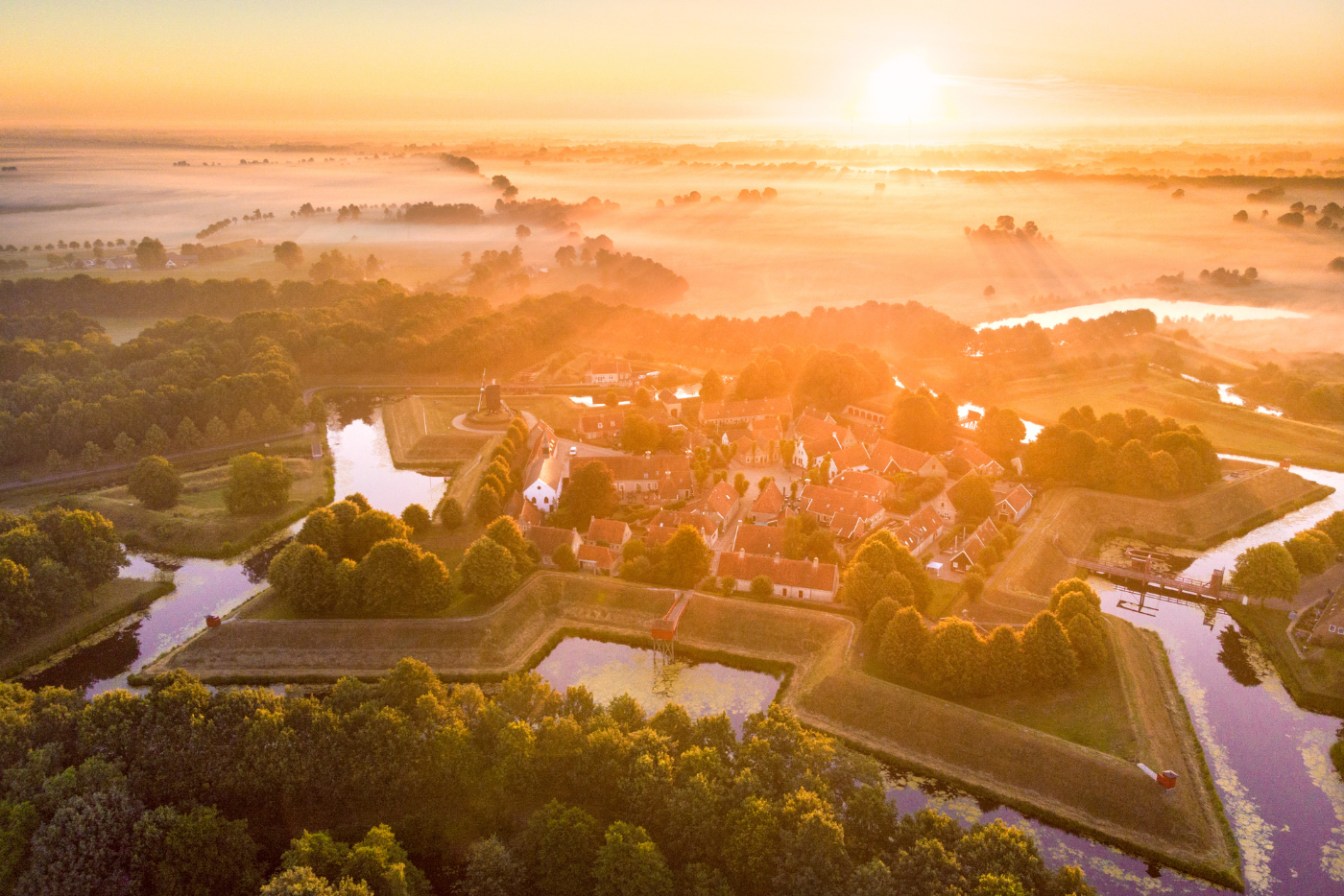 Luchtfoto van vestingdorp Bourtange bij zonsopkomst, met grachten, wallen en historische bebouwing.
