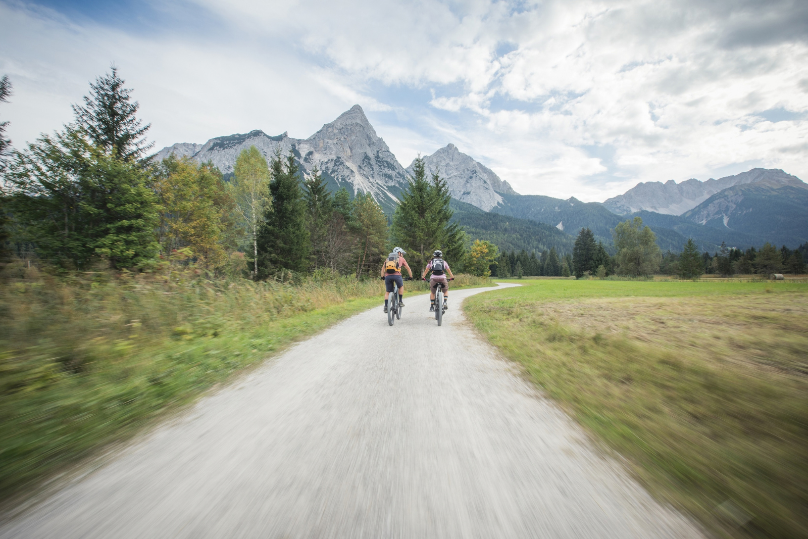 Twee e-mountainbikers fietsen over een bergpad door het dal van de Tiroler Zugspitz Arena.