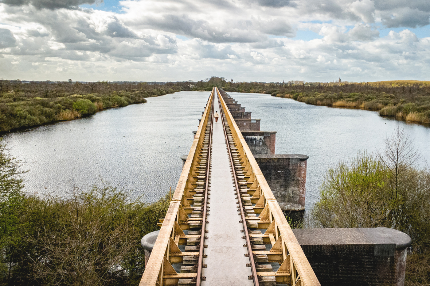 Wandelaar loopt over de historische Moerputtenbrug door natuurgebied De Moerputten bij ’s-Hertogenbosch.