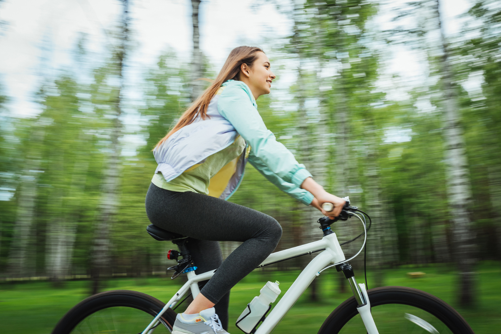 Vrouw fietst ontspannen door een groene, bosrijke omgeving.