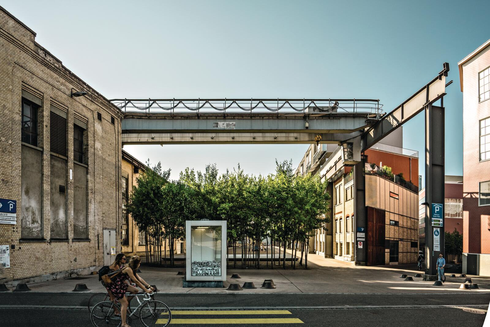 Twee fietsers rijden door een voormalig industrieel gebied in Winterthur met oude fabrieksgebouwen en staalconstructies.